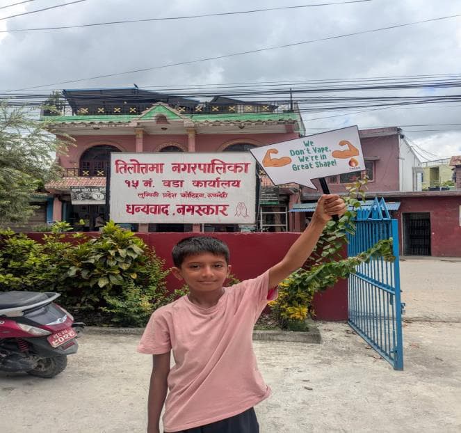 Child holding a Smoke-Free sign outside Tilottama Municipality Ward 19 office